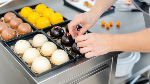 [alt=パティシエがスイーツの飾りつけをしている様子の画像。]
