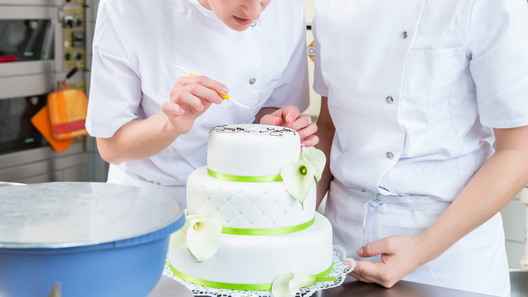 [alt=2人のパティシエが、ケーキのデコレーションや仕上げ作業をしている様子。]

