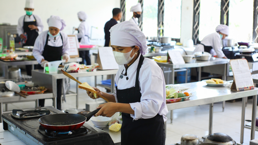 [alt=調理師を目指す学生が実習で調理をしているイメージ。]
