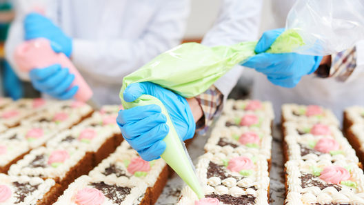 [alt=パティシエがケーキにクリームを絞ってデコレーションしている様子。]

