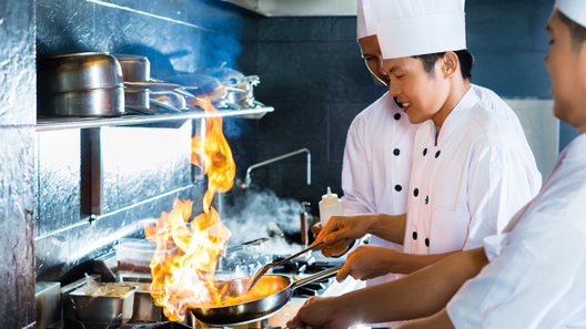 [alt=調理師が厨房で調理をしている様子。]
